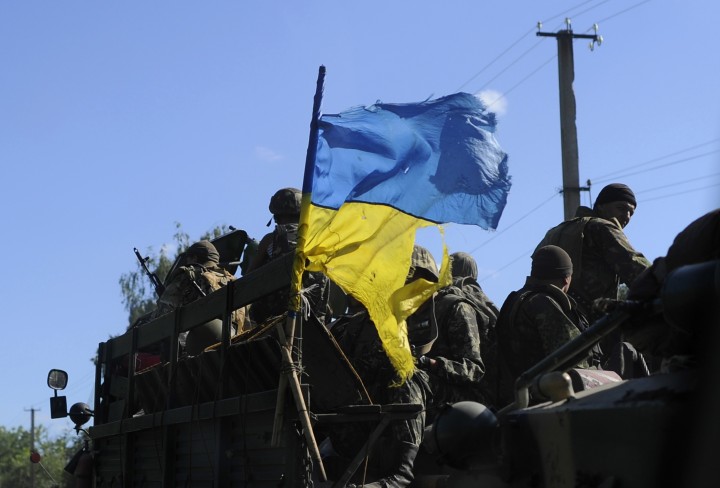Ukrainian soldiers drive a military vehicle with a torn Ukrainian flag at a checkpoint near Slaviansk in eastern Ukraine