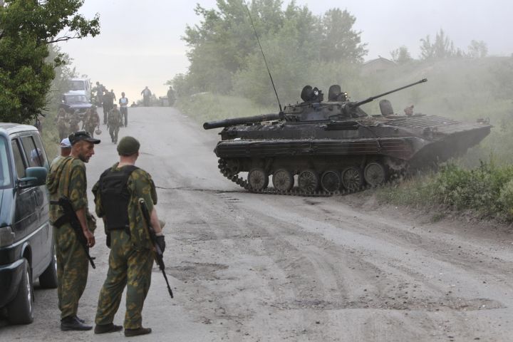 Pro-Russian activists stand near an AFV that they said was captured from the Ukrainian army during a fight outside Lysychansk