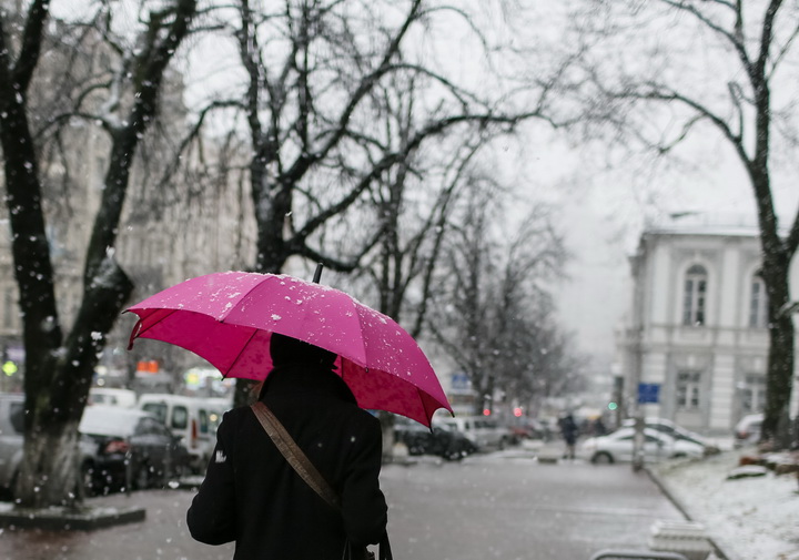 A woman holds an umbrella as she walks along a street during a snowfall in central Kiev