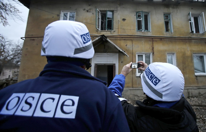 An OSCE investigator takes pictures of a building after it was damaged by recent shelling in the western part of Donetsk, eastern Ukraine