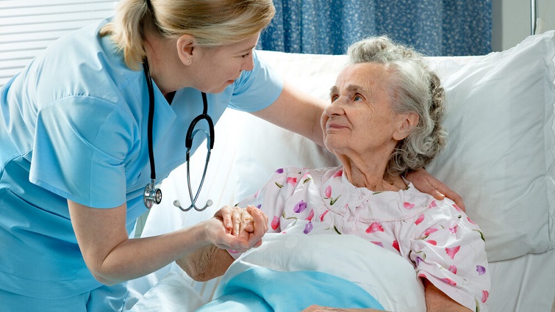 Nurse,Cares,For,Elderly,Woman,Lying,In,Bed